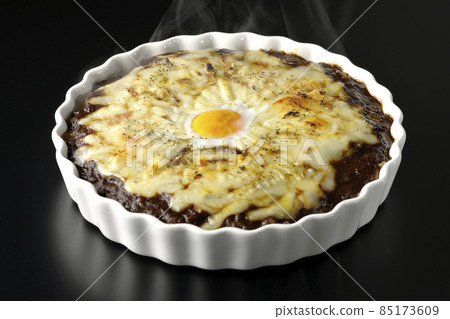 Photographed a freshly baked curry with plenty of melting cheese and eggs on a black background Photographed a freshly baked curry with plenty of melting cheese and eggs on a black background 85173609