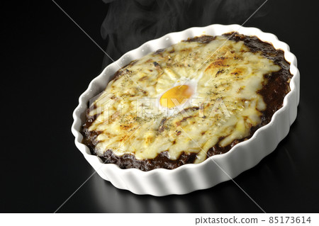 Photographed a freshly baked curry with plenty of melting cheese and eggs on a black background Photographed a freshly baked curry with plenty of melting cheese and eggs on a black background 85173614