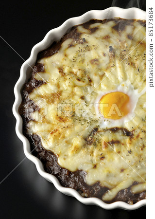 A bird's-eye view of a freshly baked curry with plenty of melted cheese and eggs on a black background A bird's-eye view of a freshly baked curry with plenty of melted cheese and eggs on a black background 85173684