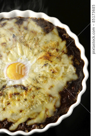 A bird's-eye view of a freshly baked curry with plenty of melted cheese and eggs on a black background A bird's-eye view of a freshly baked curry with plenty of melted cheese and eggs on a black background 85173685