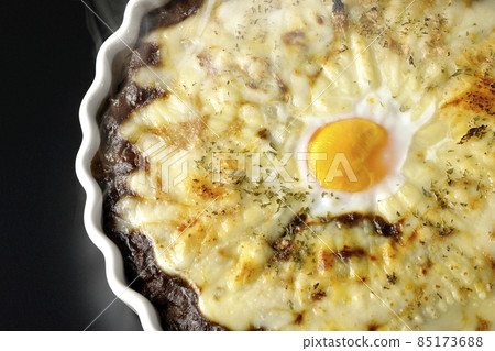 A bird's-eye view of a freshly baked curry with plenty of melted cheese and eggs on a black background A bird's-eye view of a freshly baked curry with plenty of melted cheese and eggs on a black background 85173688