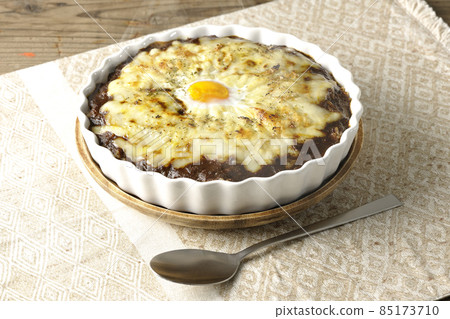 Freshly baked curry and spoon with plenty of melting cheese and eggs Freshly baked curry and spoon with plenty of melting cheese and eggs 85173710