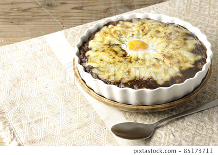 Freshly baked curry and spoon with plenty of melting cheese and eggs Freshly baked curry and spoon with plenty of melting cheese and eggs 85173711