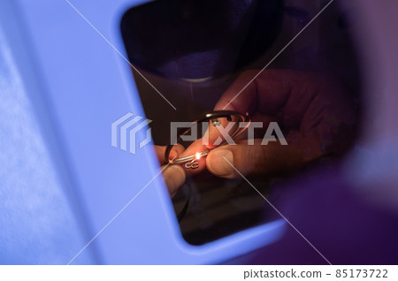 The technician solders the metal frame of the glasses. 85173722