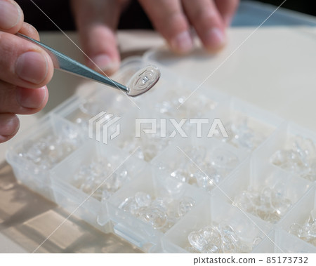 Installation of nose pads in glasses. A male technician repairs broken glasses Installation of nose pads in glasses. A male technician repairs broken glasses 85173732