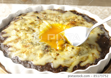 Eat a freshly cooked curry egg with plenty of melted cheese and eggs on it with a spoon. 85173752