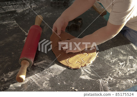 Hands dough and a rolling pin close-up boy helps mom in the kitchen make cookies 85175524