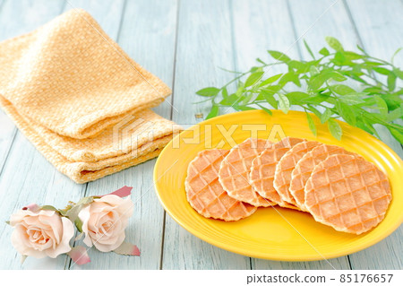 Butter waffles on a yellow plate and roses on a yellow cloth 85176657