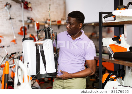 Man choosing shoulder sprayer in gardening tools store Man choosing shoulder sprayer in gardening tools store 85176965
