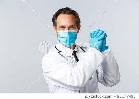 Covid-19, preventing virus, healthcare workers and vaccination concept. Encouraged and determined optimistic doctor in medical mask and gloves, clench hands together in victory 85177495