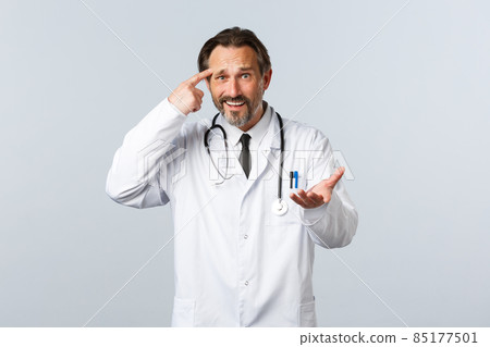 Covid-19, coronavirus outbreak, healthcare workers and pandemic concept. Upset male doctor scolding patient acting stupid, pointing at temple and raise hand in dismay, disappointed in person 85177501