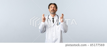 Covid-19, coronavirus outbreak, healthcare workers and pandemic concept. Hopeful doctor in panic looking up sky, pleading god while cross fingers, make wish, wearing white coat Covid-19, coronavirus outbreak, healthcare workers and pandemic concept. Hopeful doctor in panic looking up sky, pleading god while cross fingers, make wish, wearing white coat 85177569