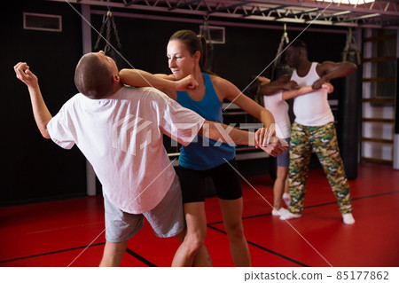 Active girl conducts painful grip on self-defense training in gym Active girl conducts painful grip on self-defense training in gym 85177862
