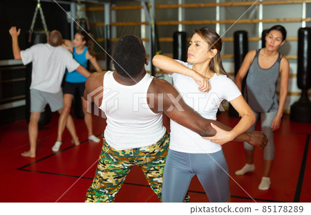 Latino woman is training with man on self-defense course in gym Latino woman is training with man on self-defense course in gym 85178289