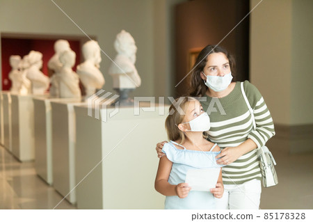 Woman visitor with daughter looking at exhibition in museum Woman visitor with daughter looking at exhibition in museum 85178328