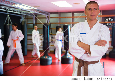 Man in kimono during group karate training Man in kimono during group karate training 85178374