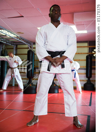 African-american man in kimono standing in gym African-american man in kimono standing in gym 85178376