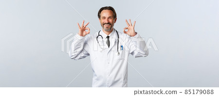 Covid-19, coronavirus outbreak, healthcare workers and pandemic concept. Satisfied happy doctor guarantee quality. Therapist show okay gesture and smiling pleased, advertise promo 85179088