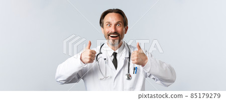 Covid-19, preventing virus, healthcare workers and vaccination concept. Excited thrilled doctor in white coat totally agree, thumbs-up in approval and smiling astonished, recommend product Covid-19, preventing virus, healthcare workers and vaccination concept. Excited thrilled doctor in white coat totally agree, thumbs-up in approval and smiling astonished, recommend product 85179279