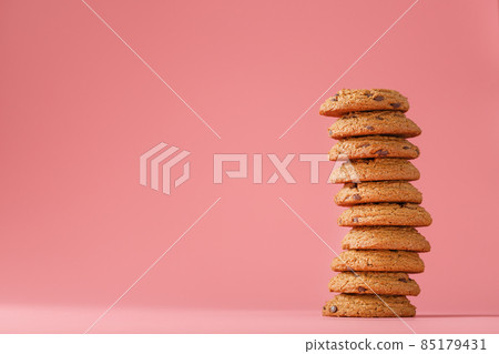 Oatmeal cookies with pieces of chocolate stand like a tower on a pink background Oatmeal cookies with pieces of chocolate stand like a tower on a pink background 85179431