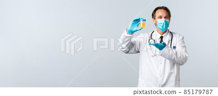 Covid-19, preventing virus, healthcare workers and vaccination concept. Pleased smiling doctor in medical mask and gloves show urine sample, satisfied with clean test result, white background 85179787
