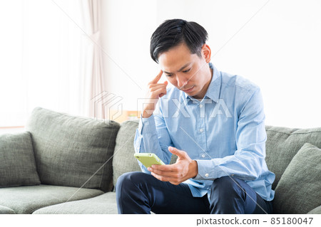 考慮一個男人在房間裡看智能手機 考慮一個男人在房間裡看智能手機 85180047