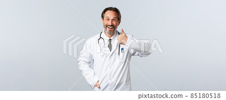 Covid-19, coronavirus outbreak, healthcare workers and pandemic concept. Happy smiling male doctor in white coat smiling pleased, show thumbs-up, recommend and promote clinic services 85180518