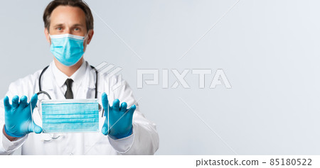 Covid-19, virus, healthcare workers and vaccination concept. Middle-aged doctor in PPE, recommend medical mask brand, explain how wear mask to prevent catching coronavirus disease 85180522