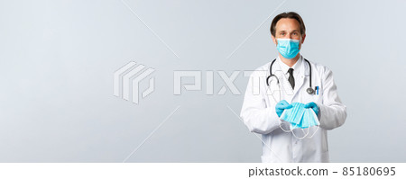 Covid-19, preventing virus, healthcare workers and vaccination concept. Helpful male doctor in PPE handing over medical masks to patients sick coronavirus, explain importance of social distancing Covid-19, preventing virus, healthcare workers and vaccination concept. Helpful male doctor in PPE handing over medical masks to patients sick coronavirus, explain importance of social distancing 85180695