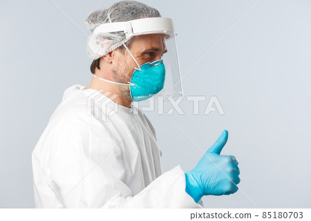 Covid-19, preventing virus, healthcare workers and vaccination concept. Profile of cheerful doctor in personal protective equipment showing thumb-up patient, ensure all good, nothing worry about Covid-19, preventing virus, healthcare workers and vaccination concept. Profile of cheerful doctor in personal protective equipment showing thumb-up patient, ensure all good, nothing worry about 85180703
