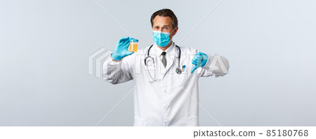 Covid-19, preventing virus, healthcare workers and vaccination concept. Disappointed doctor in medical mask and gloves show urine sample, thumbs-down have bad test result, white background 85180768