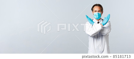 Covid-19, preventing virus, healthcare workers and vaccination concept. Serious determined doctor fighting coronavirus tell what not do, cross arms in stop or prohibition gesture 85181713