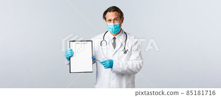 Covid-19, preventing virus, healthcare workers and vaccination concept. Worried and confused male doctor in medical mask and gloves, pointing at clipboard with information or diagnose Covid-19, preventing virus, healthcare workers and vaccination concept. Worried and confused male doctor in medical mask and gloves, pointing at clipboard with information or diagnose 85181716
