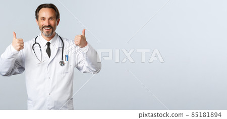 Covid-19, coronavirus outbreak, healthcare workers and pandemic concept. Satisfied cheerful male doctor in white coat showing thumbs-up in approval. Therapist recommend medication Covid-19, coronavirus outbreak, healthcare workers and pandemic concept. Satisfied cheerful male doctor in white coat showing thumbs-up in approval. Therapist recommend medication 85181894