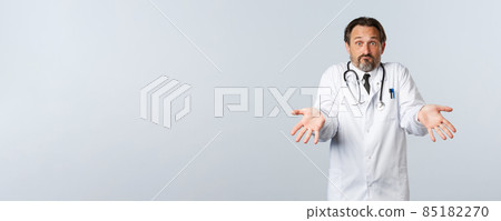 Covid-19, coronavirus outbreak, healthcare workers and pandemic concept. Confused worried male doctor made mistake explaining to hostal worker, showing empty hands and shrugging 85182270
