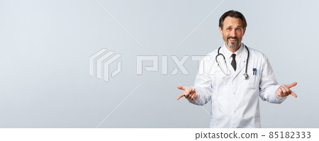 Covid-19, coronavirus outbreak, healthcare workers and pandemic concept. Questioned and confused male doctor in white coat, shrugging with hands spread sideways in dismay, hear nonsense Covid-19, coronavirus outbreak, healthcare workers and pandemic concept. Questioned and confused male doctor in white coat, shrugging with hands spread sideways in dismay, hear nonsense 85182333