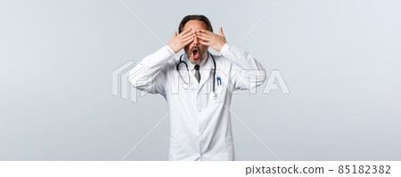 Covid-19, coronavirus outbreak, healthcare workers and pandemic concept. Excited surprised male doctor in white coat close eyes and gasping amazed, anticipating big news, white background 85182382