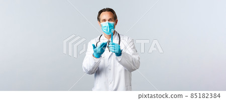 Covid-19, preventing virus, healthcare workers and vaccination concept. Satisfied smiling doctor in medical mask and gloves pointing at test-tube with vaccine sample, pleased with good result 85182384