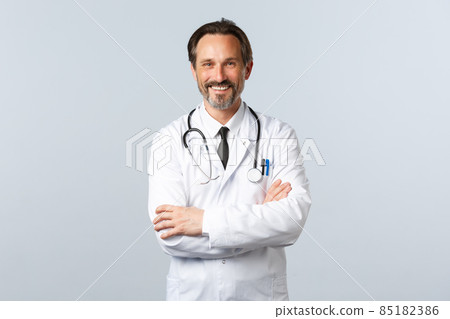 Covid-19, coronavirus outbreak, healthcare workers and pandemic concept. Enthusiastic smiling doctor, physician in white coat looking enthusiastic, cross arms chest, listening to patient Covid-19, coronavirus outbreak, healthcare workers and pandemic concept. Enthusiastic smiling doctor, physician in white coat looking enthusiastic, cross arms chest, listening to patient 85182386