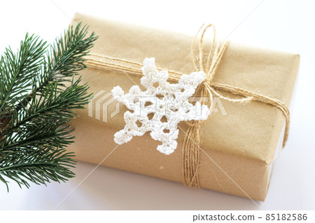 Christmas and New Years background close-up. Gift box wrapped in kraft paper with jute cord. Decorated with a crocheted snowflake and a branch 85182586
