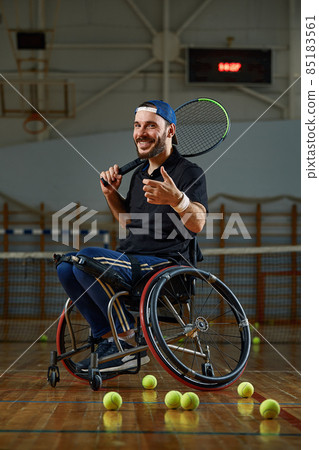 Young man in wheelchair playing tennis on court Young man in wheelchair playing tennis on court 85183561
