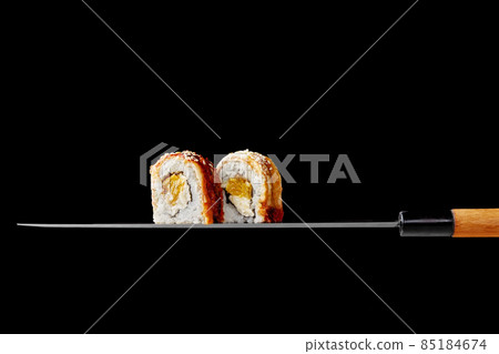 Two unagi rolls with cream cheese and orange on blade of Japanese knife Two unagi rolls with cream cheese and orange on blade of Japanese knife 85184674
