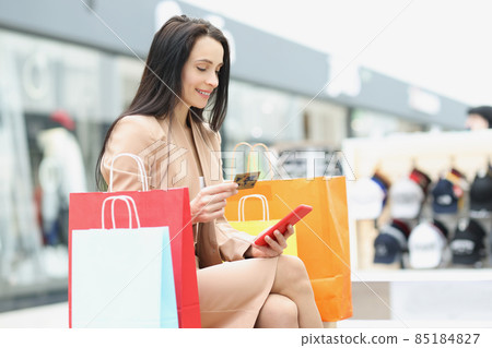 Woman shopaholic make order via smartphone and pay with credit card Woman shopaholic make order via smartphone and pay with credit card 85184827