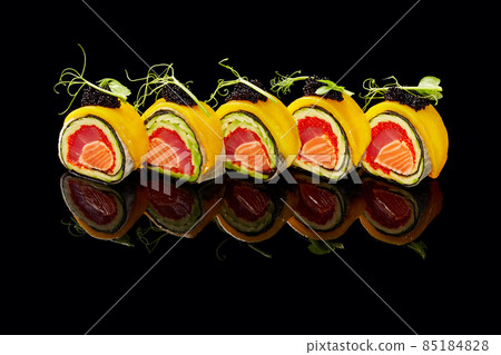 No-rice sushi roll with tuna, salmon, tobiko, avocado in mamenori topped with mango, caviar on black background No-rice sushi roll with tuna, salmon, tobiko, avocado in mamenori topped with mango, caviar on black background 85184828