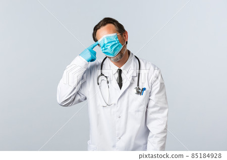 Covid-19, preventing virus, healthcare workers and vaccination concept. Tired and distressed doctor fighting coronavirus, exhausted work, pull mask on whole face and make shot gun gesture near head Covid-19, preventing virus, healthcare workers and vaccination concept. Tired and distressed doctor fighting coronavirus, exhausted work, pull mask on whole face and make shot gun gesture near head 85184928