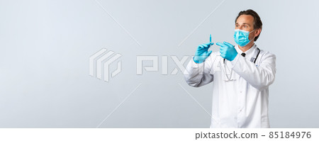 Covid-19, preventing virus, healthcare workers and vaccination concept. Middle-aged doctor in medical mask and gloves holding syringe with coronavirus vaccine or hiv prep, prepare shot for patient 85184976