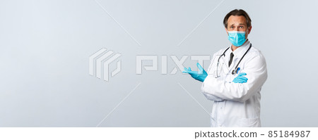 Covid-19, preventing virus, healthcare workers and vaccination concept. Skeptical confused doctor in medical mask and gloves pointing disappointed left, express frustration and disagreement 85184987