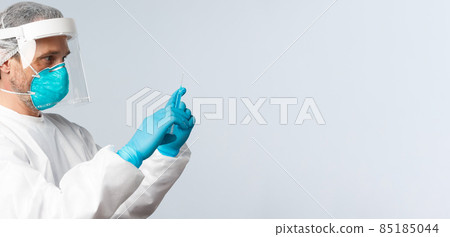 Covid-19, preventing virus, healthcare workers and vaccination concept. Profile shot of doctor in personal protective equipment fill syringe with coronavirus vaccine, treating sick patient 85185044