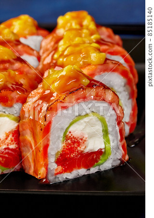 Closeup of uramaki roll with cream cheese, tobiko, avocado, seared salmon and mango 85185140