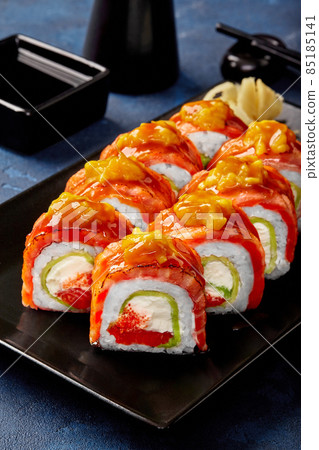 Uramaki roll with cream cheese, tobiko, avocado, seared salmon, mango served with soy sauce 85185141